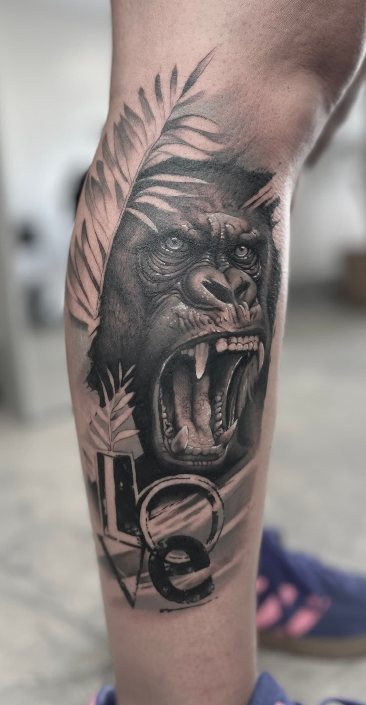 Roaring gorilla among palm leaves with lettering below, in black and grey on the calf.