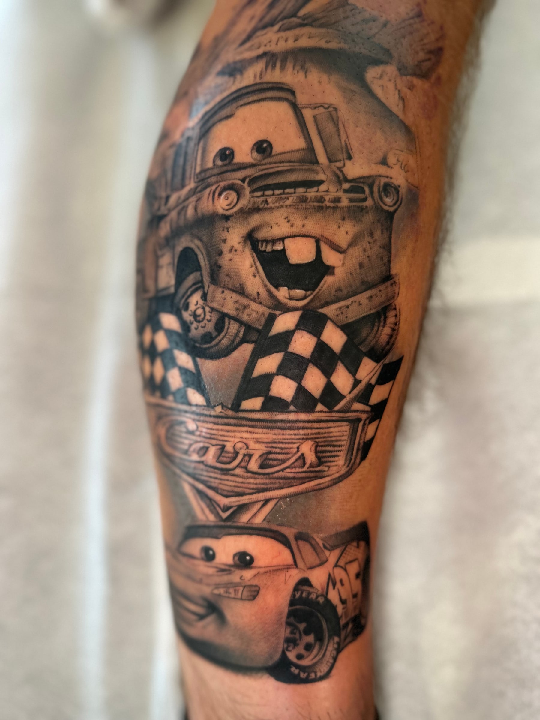 Mater and Lightning McQueen from Cars with chequered flags and the Cars logo, in black and grey on the calf.