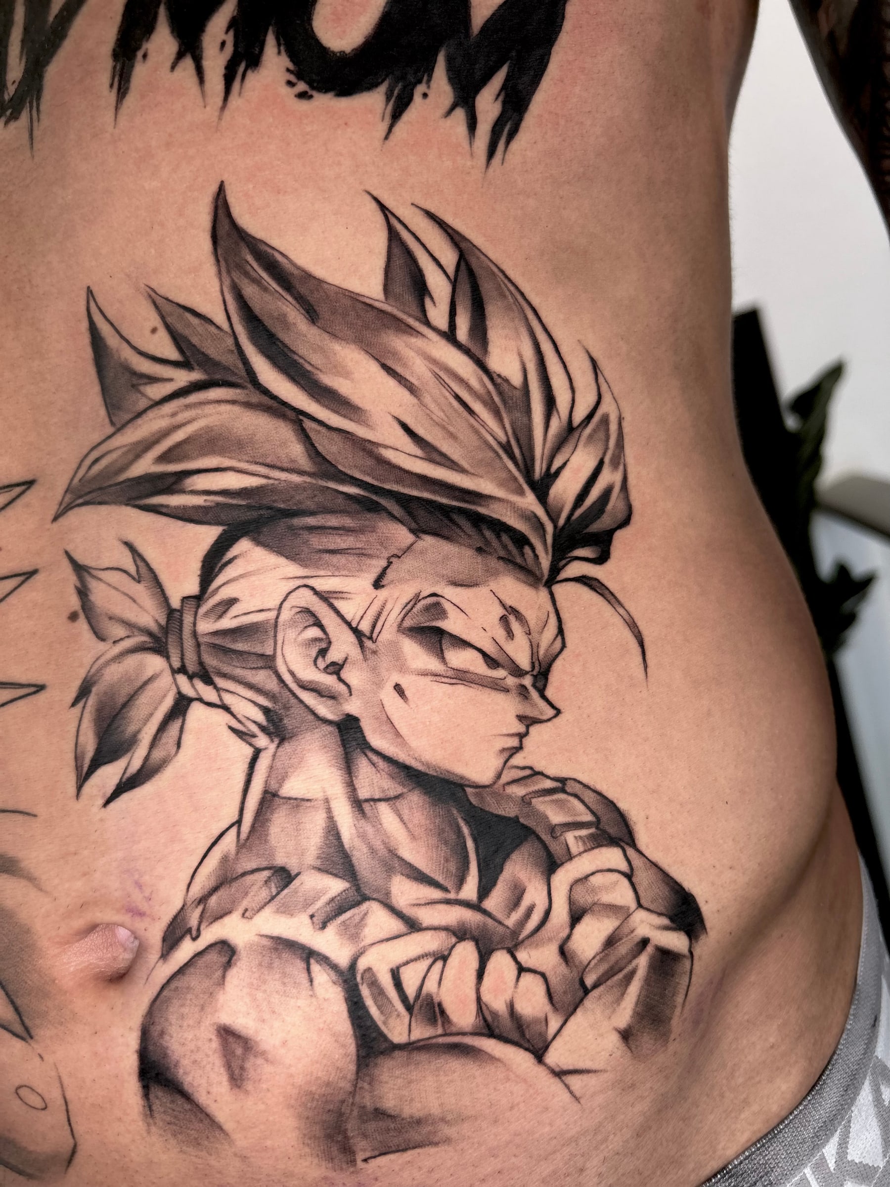Anime warrior with spiked hair and crossed arms, shaded like a pencil sketch, across the ribs and stomach.